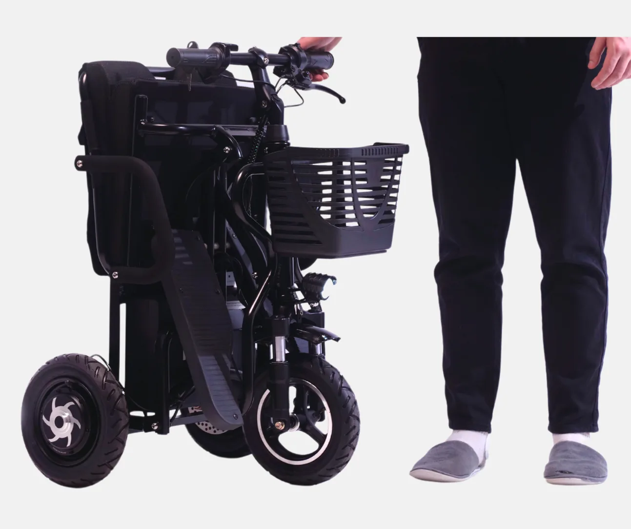 A rider wheels the folded eTricycle 2 by its handlebar